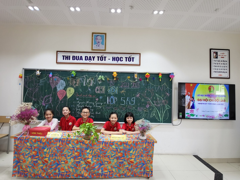 A group of children sitting at a table in front of a chalkboard

Description automatically generated with medium confidence