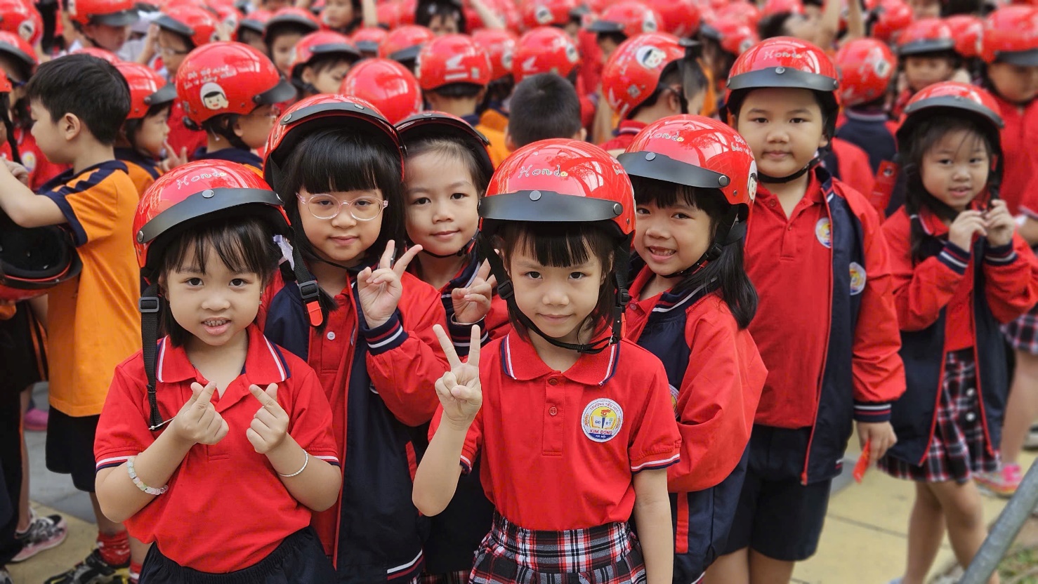 A group of children wearing red helmets

Description automatically generated