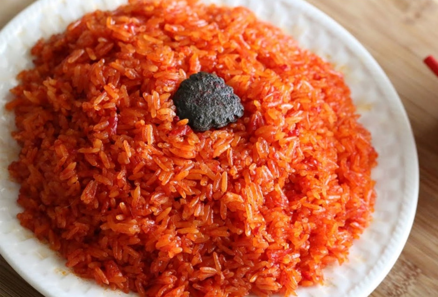 A plate of rice with a black object on top

AI-generated content may be incorrect.