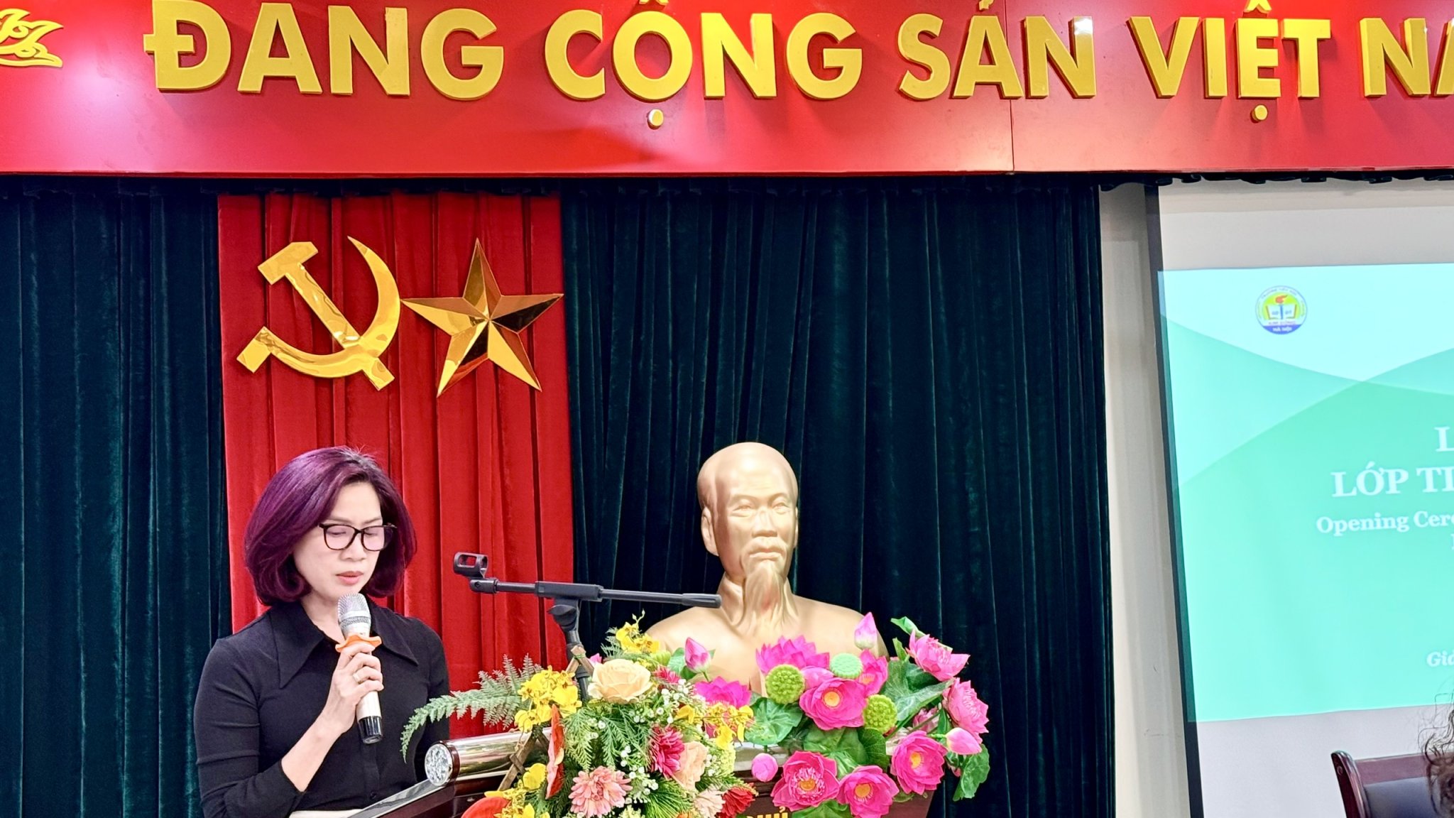 A person standing in front of a podium with a microphone and flowers
AI-generated content may be incorrect.