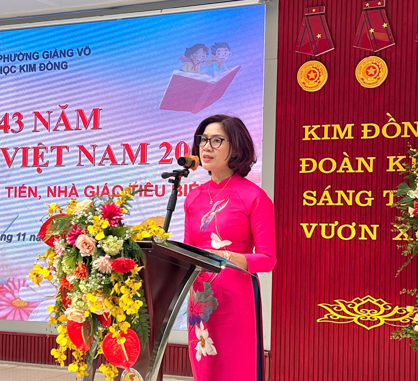 A person standing at a podium with a microphone and flowers

AI-generated content may be incorrect.