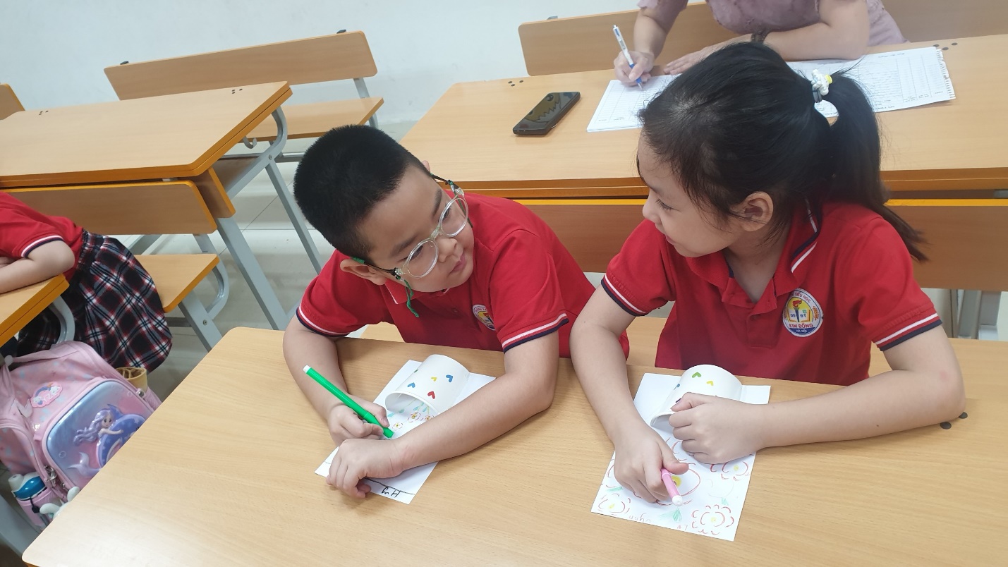 A child and child sitting at a desk
Description automatically generated