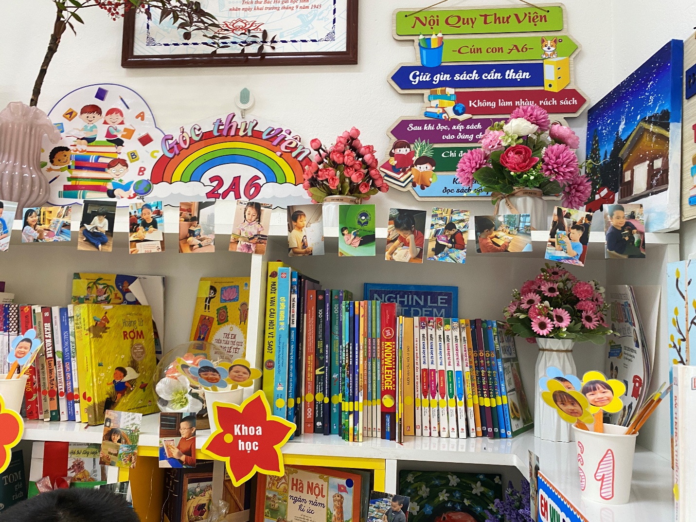 A shelf with books and flowers
Description automatically generated