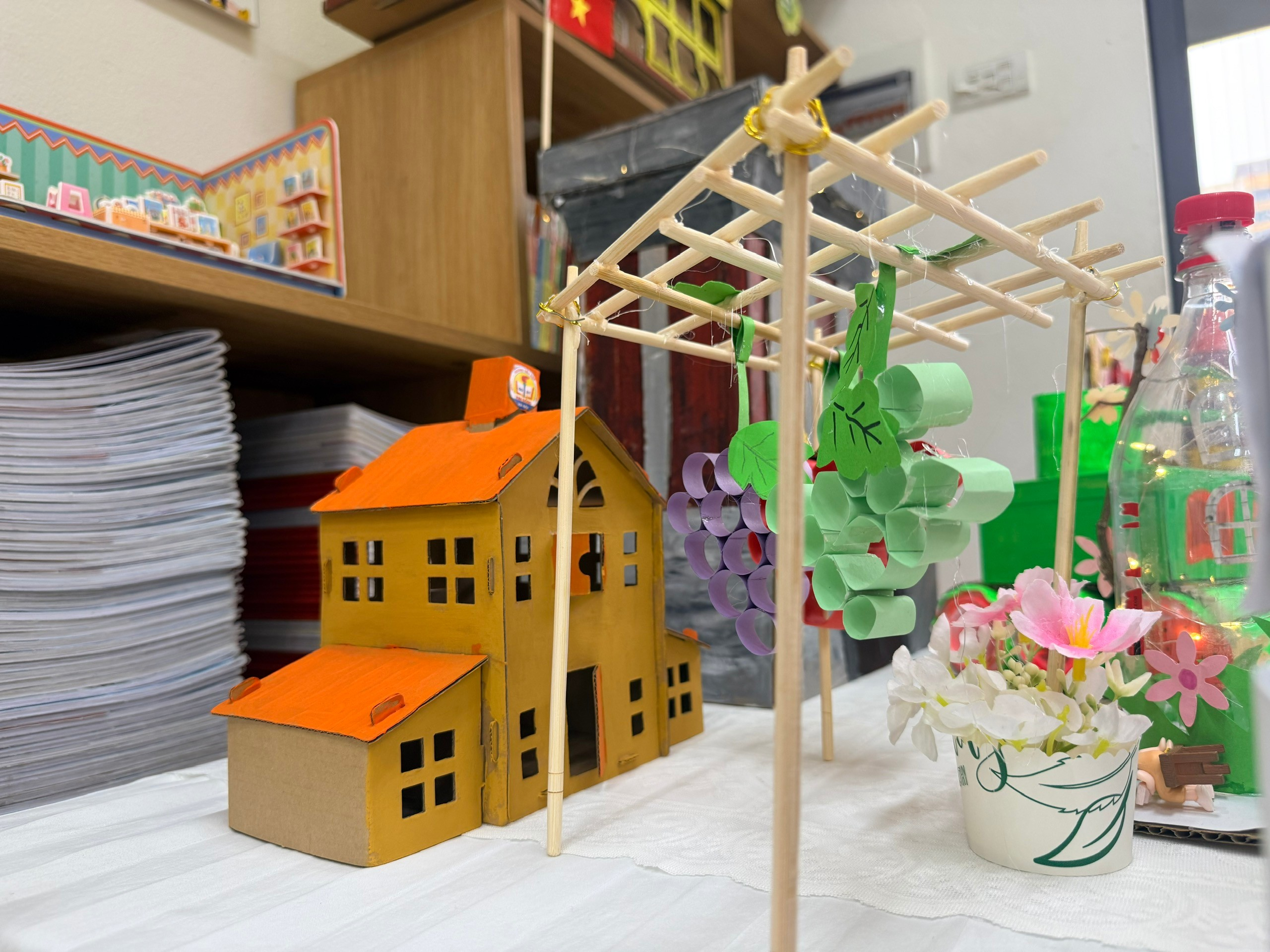 A paper house and flowers on a table
Description automatically generated