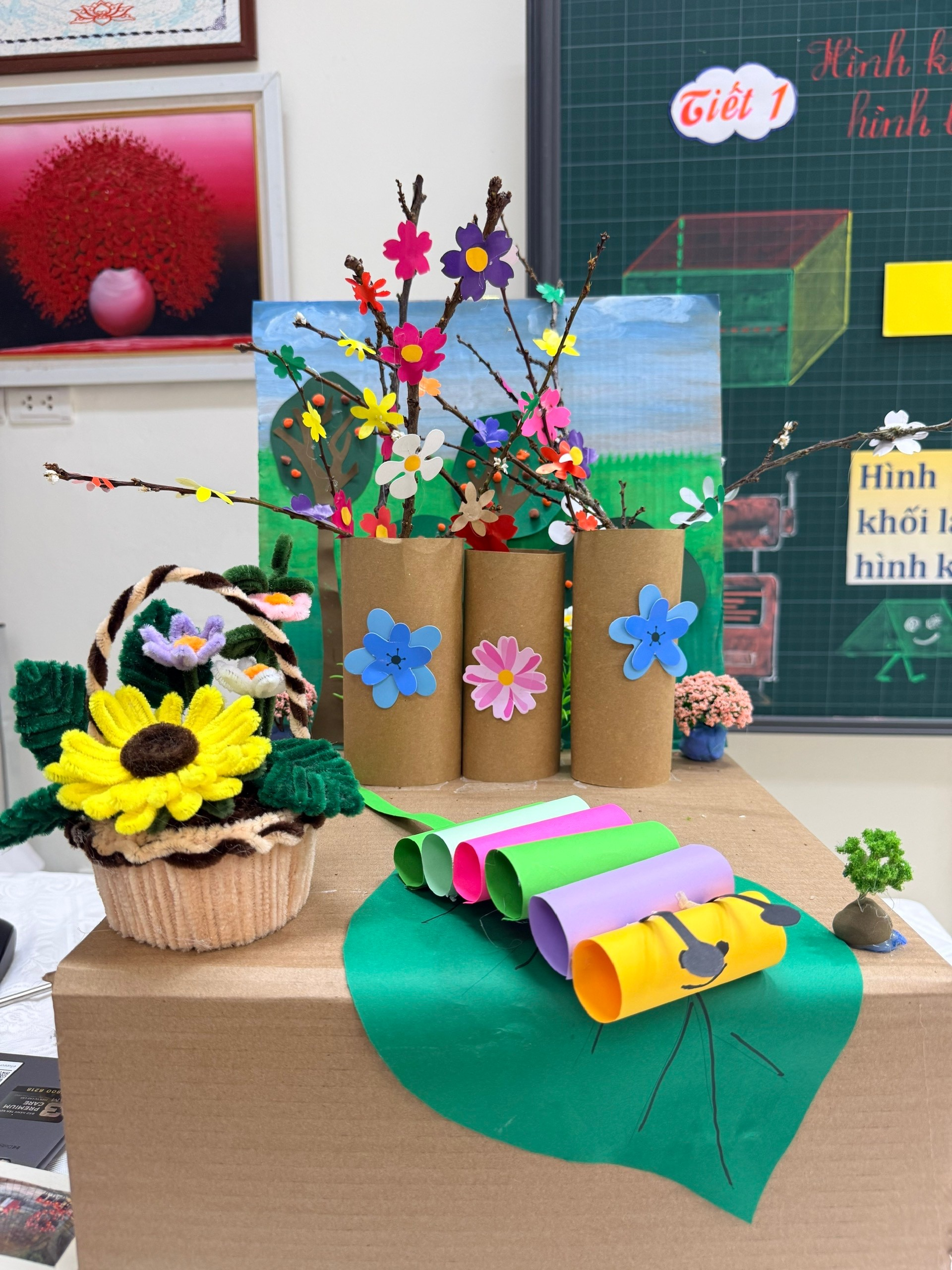A cardboard box with flowers and a basket of paper rolls
Description automatically generated