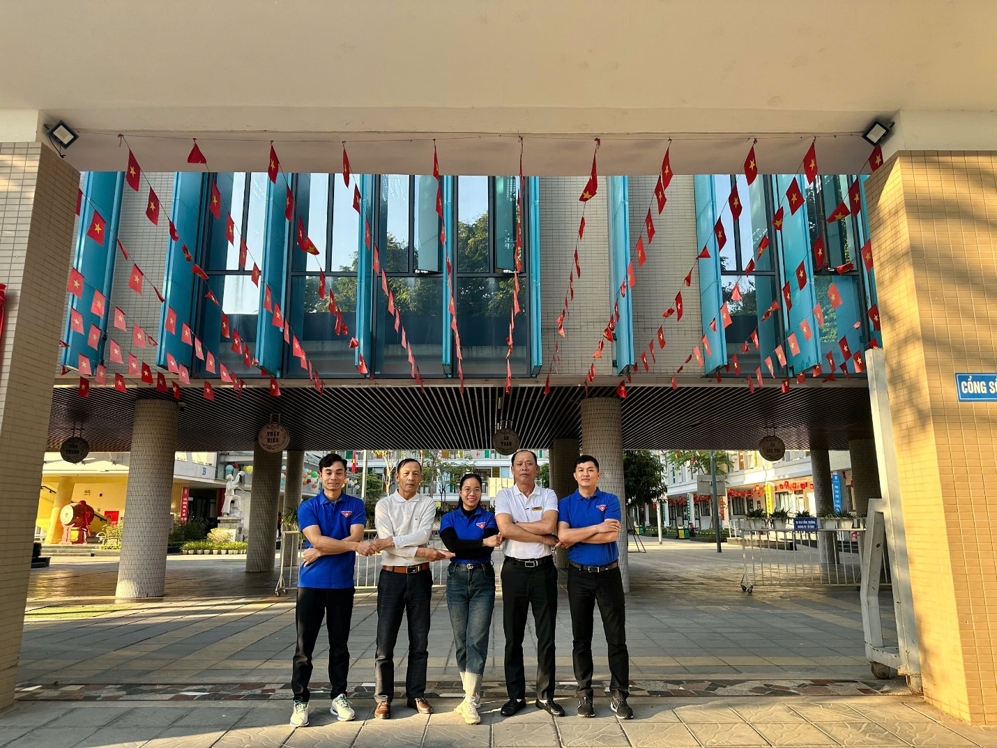 A group of people standing under a building
Description automatically generated