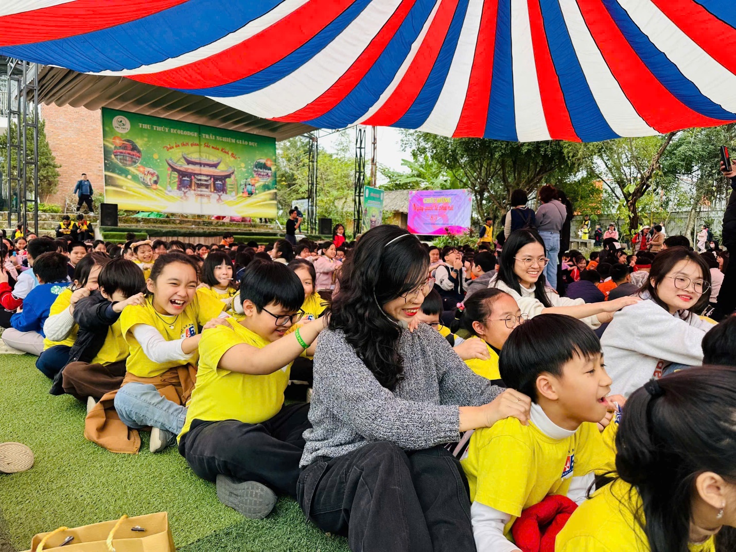 A group of children sitting on the ground under a tent
AI-generated content may be incorrect.