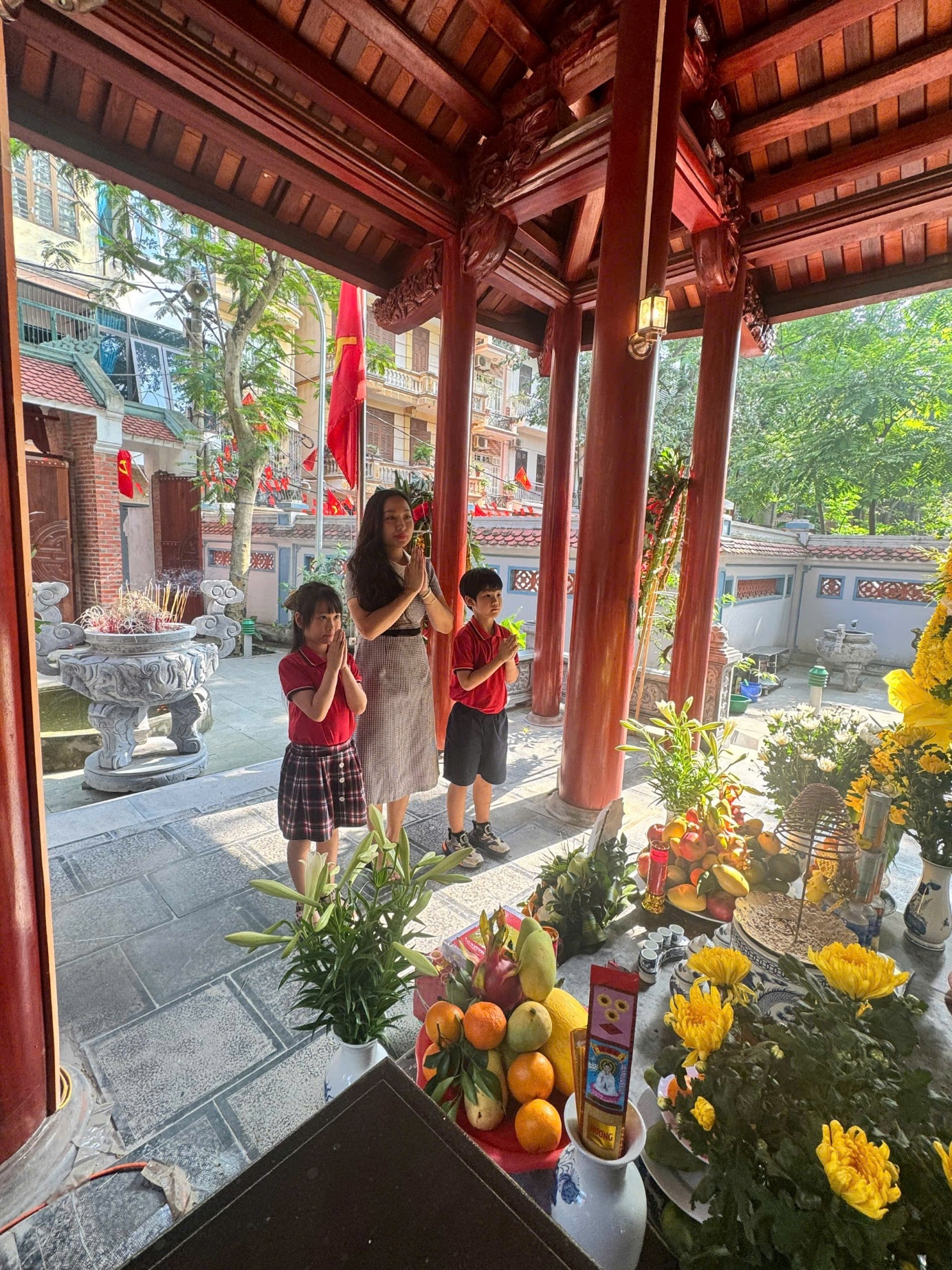 A person and kids standing in a shrine
Description automatically generated