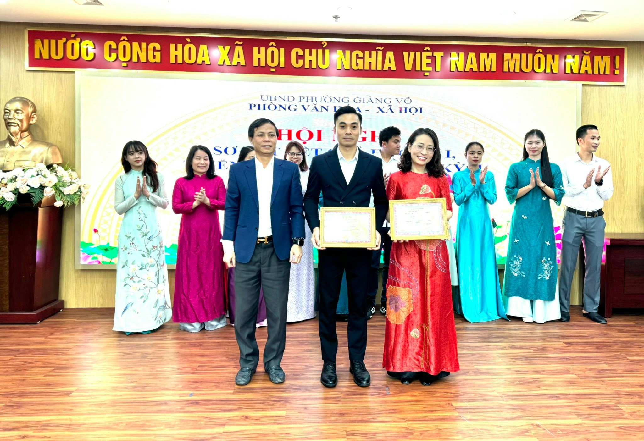 A group of people standing in front of a stage

Description automatically generated