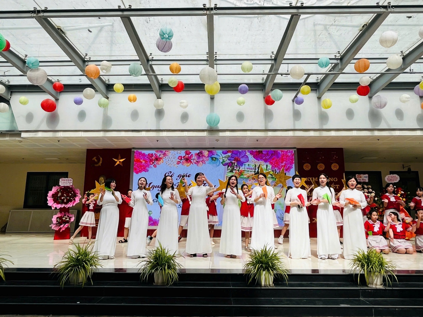 A group of women in white dresses performing on a stage
Description automatically generated